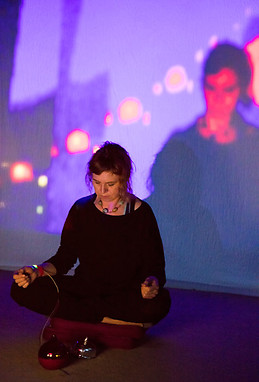 Alicia Champlin sitting in meditation pose with biofeedback projection